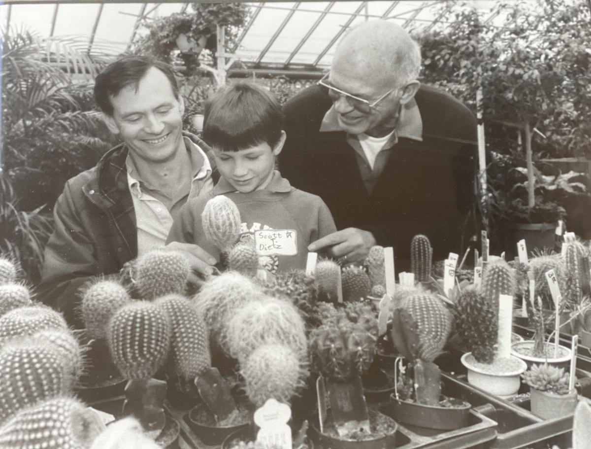 Black and white photo of two men and boy looking at cactuses